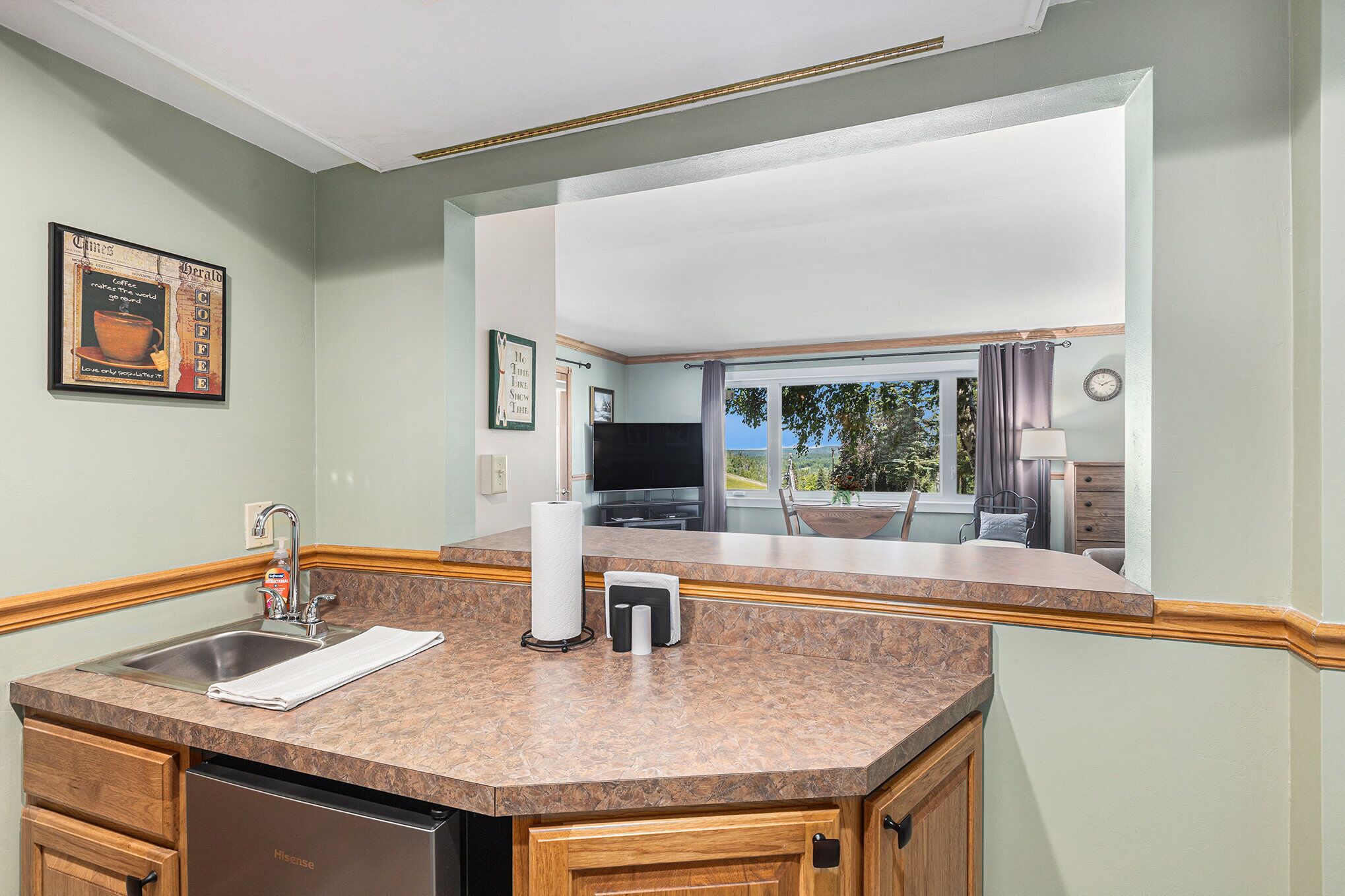 A kitchen with a sink, a dish soap dispenser, a paper towel holder, and a dish rack.