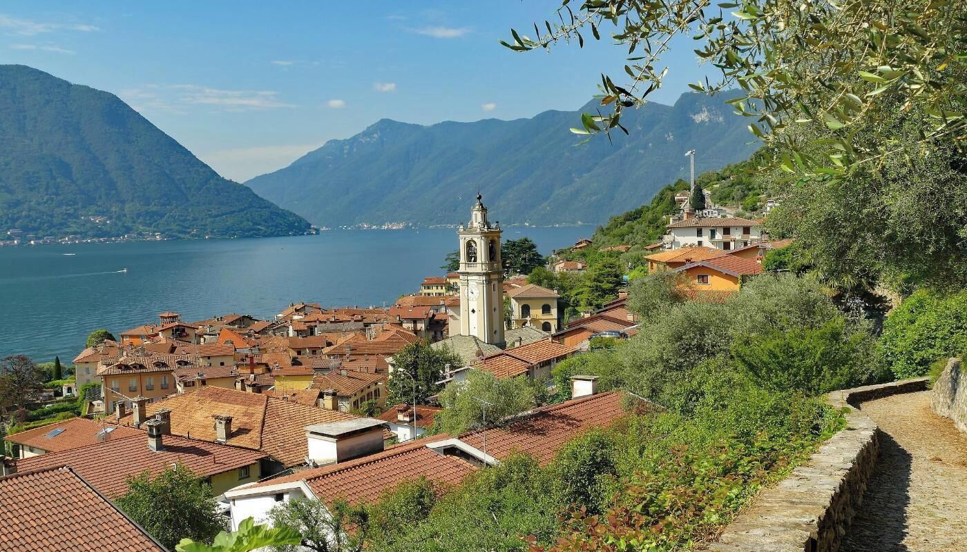Une ville côtière aux bâtiments aux toits de tuiles rouges, dotée d’un imposant beffroi et offrant une vue sur la mer et les montagnes.