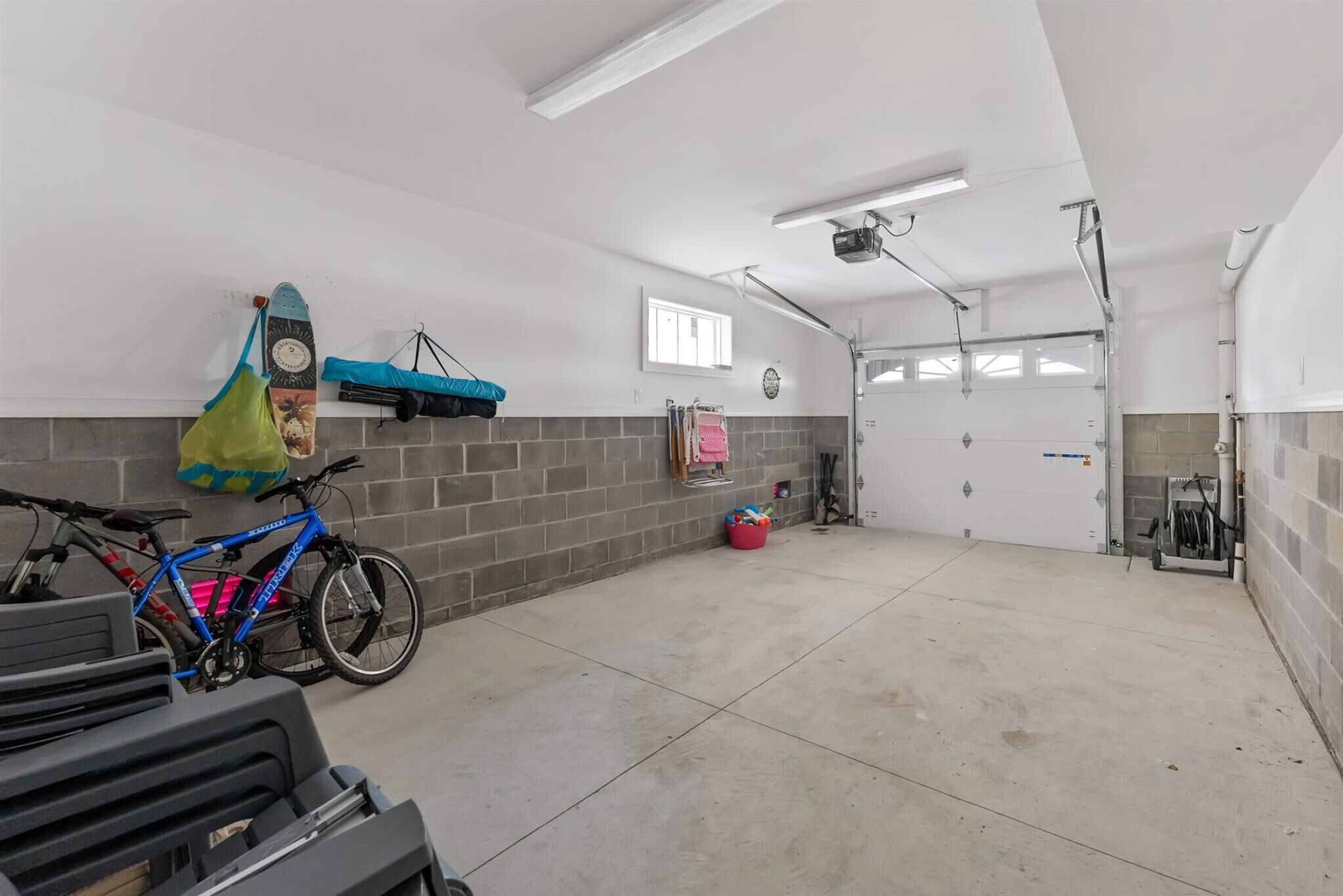 En ren og veloplyst garage med betongulv, en blå cykel og et vægmonteret stativ.