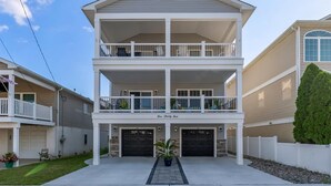 A two-story house with a covered front porch, two garages, and a small garden area. - Modern Beach Condo: Walk to Beach & Boardwalk (Wildwood)