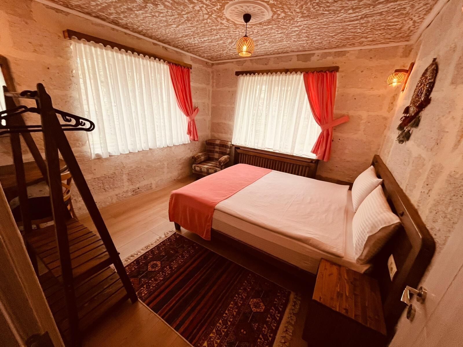 Una camera da letto con un letto, una sedia, un tavolino, una scala in legno e un tappeto decorato.