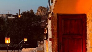 A stone staircase leading to a red door, with a lamp post and a view of a mountain in the background. - Cherrykonak cappadocia (Nevsehir)