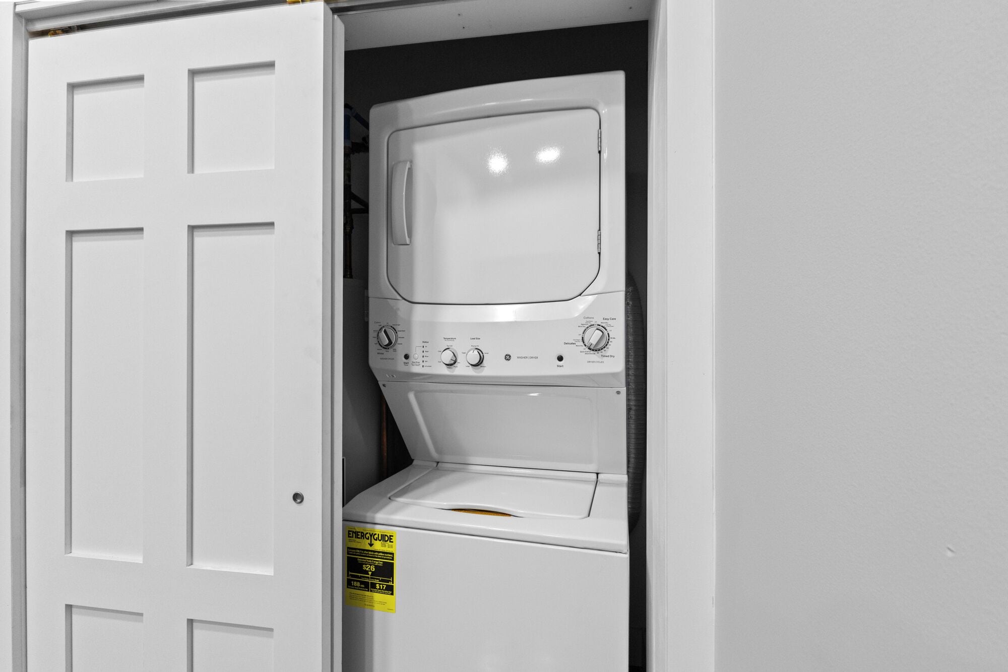 Une machine à laver blanche se trouve dans une buanderie, avec une porte.
