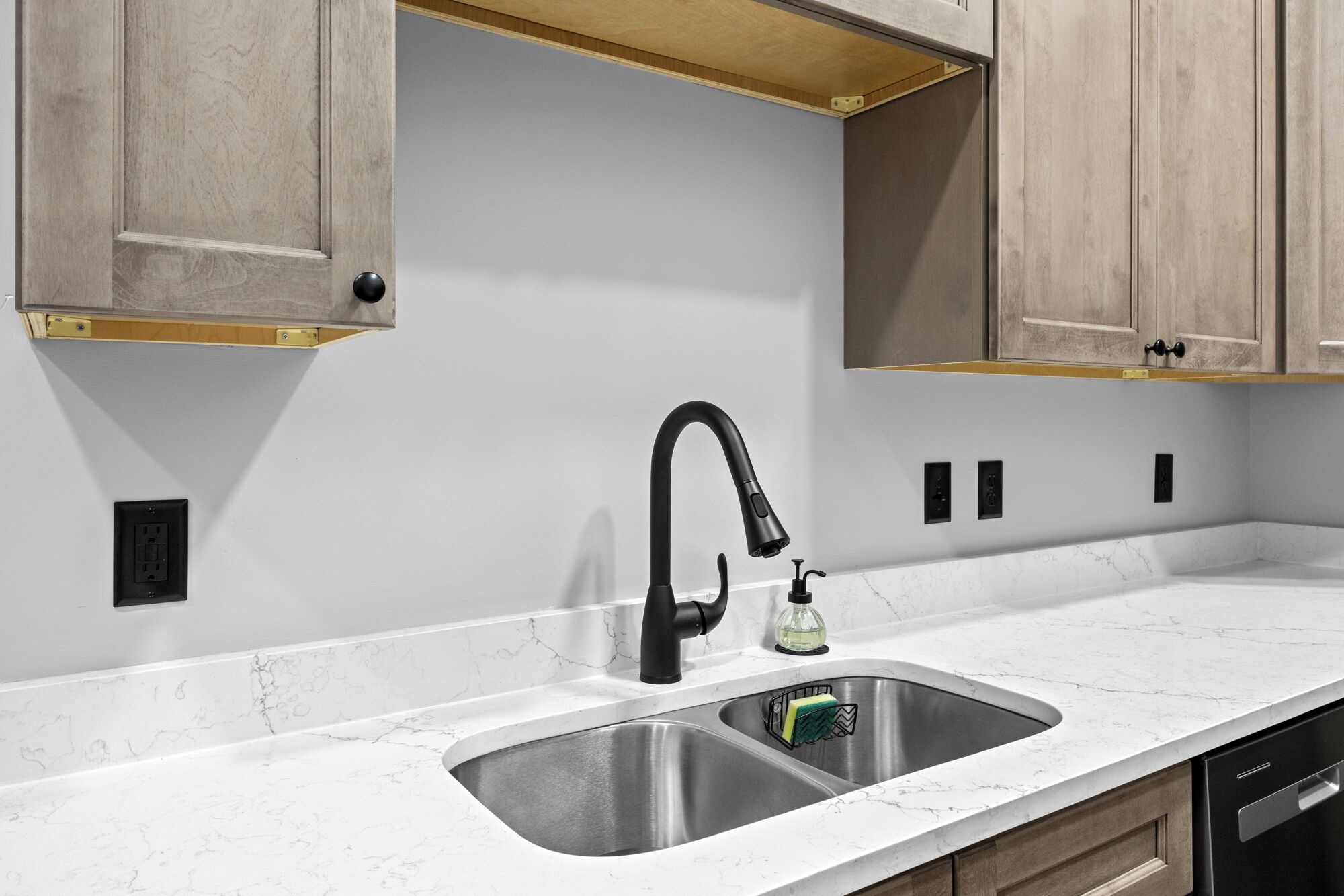 A kitchen with a double sink, a modern faucet, and wooden cabinets.