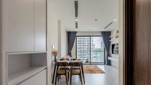 Un comedor moderno con una mesa preparada para cuatro personas, un sofá y vistas de un paisaje urbano a través de amplias ventanas.