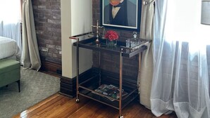 A room with a brick wall, a framed picture of a horse, a glass coffee table with decorative items, and a green chair.