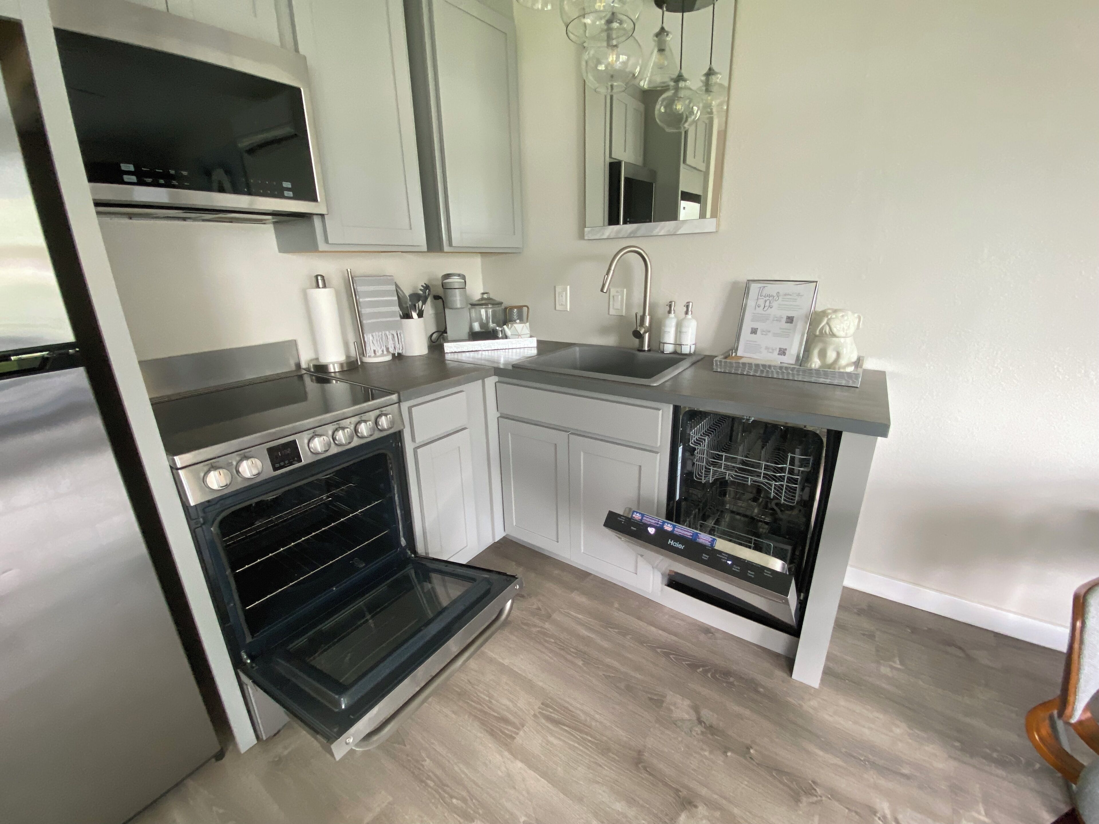 A modern kitchen with stainless steel appliances, white cabinetry, and a built-in dishwasher.