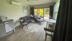 A living room with a sofa, chairs, a small table, a ceiling fan, and a view of the outdoors through large windows. - Private Lakefront Cottage, Bright, Peaceful, and Perfect for a Relaxing Escape. (Clermont)