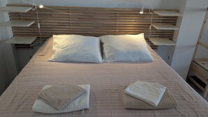 Un lit bien fait, avec une couvre-lit à rayures, deux oreillers et deux serviettes pliées.