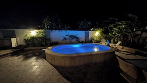 Une piscine dotée d’une terrasse carrelée et d’une bordure en pierre.