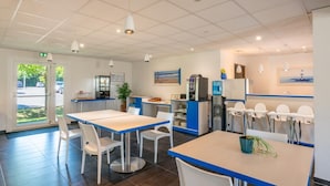 Un comedor moderno con mesas, sillas, dispensador de agua y refrigerador.