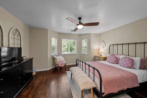 Une chambre à coucher avec un lit, une commode, un téléviseur et un ventilateur de plafond.
