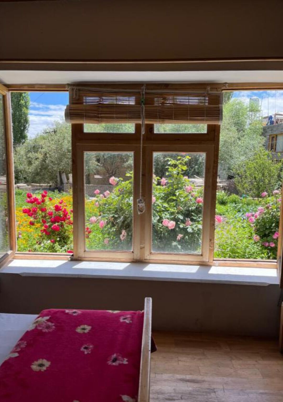 A room with a large window overlooking a garden with pink flowers.