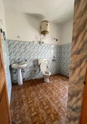 Une salle de bain équipée d’un lavabo, de toilettes et d’un chauffe-eau mural.
