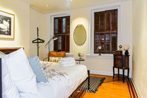 Ein Hotelzimmer mit einem Bett, einem Nachttisch mit Lampe, einem Spiegel und einem Fenster mit Rollläden.