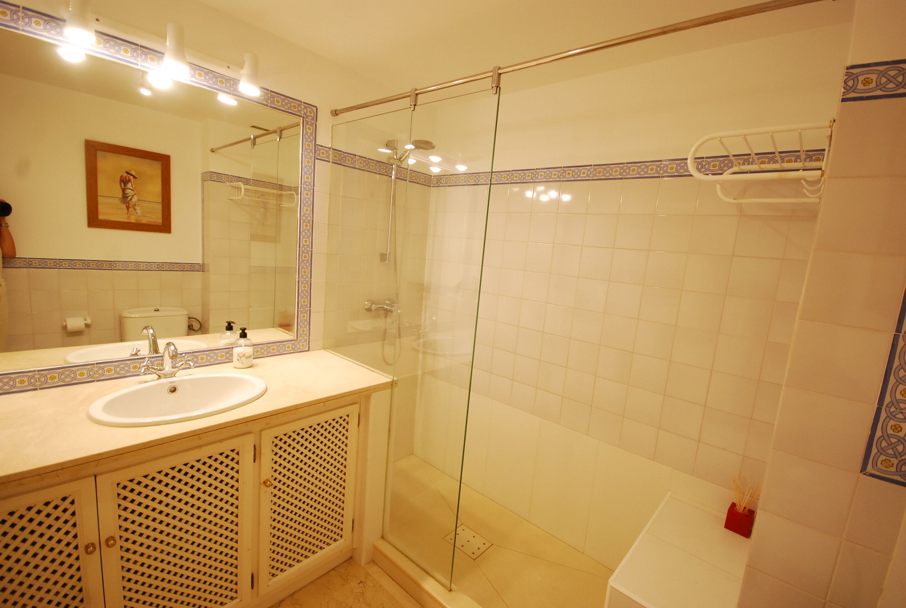 A bathroom with a glass-enclosed shower, a sink, and a mirror.
