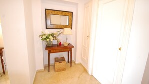 A hallway with a wooden console table, a mirror, a lamp, and a basket. - Apartment in Guadalmina Alta next to the Golf and shopping center. (San Pedro de Alcantara)