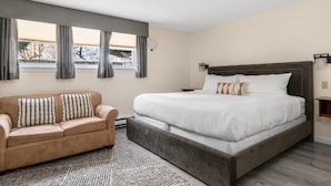 Une chambre à coucher avec un lit, un canapé et une fenêtre avec des rideaux.
