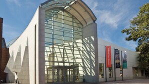 A modern building with a curved glass facade and a brick base. - Premium Double Queen Studio | The Beverly | Minutes to Peabody Essex Museum (Beverly)