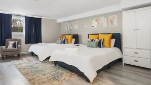 A hotel room with two beds, a wardrobe, and a chair. - Premium Double Queen Studio | The Beverly | Minutes to Peabody Essex Museum (Beverly)