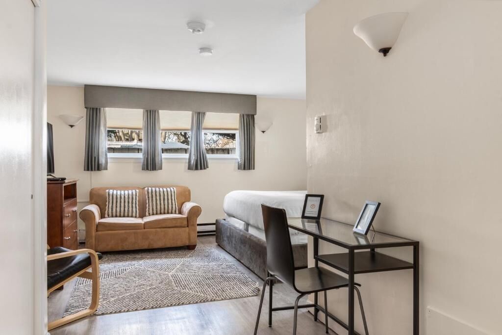 A compact living space with a sofa, a small desk, and a chair.