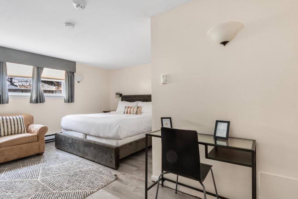 A bedroom with a bed, a desk, a chair, and a sofa.