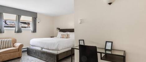 A bedroom with a bed, a desk, a chair, and a sofa.