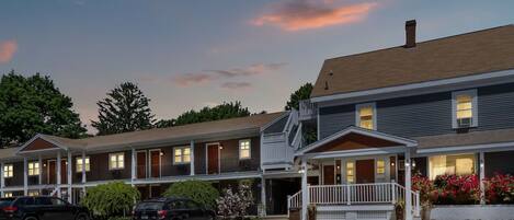 A motel with multiple units, a parking lot, and a landscaped front yard with flowers.