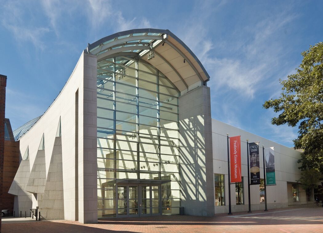 A modern building with a curved glass facade and a brick base.