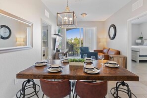A dining area with a wooden table set for four, surrounded by leather chairs. - Vista Cay Swanky (Orlando)