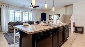A modern kitchen with a large island, dark cabinetry, and pendant lighting. - Solterra Swanky (Davenport)