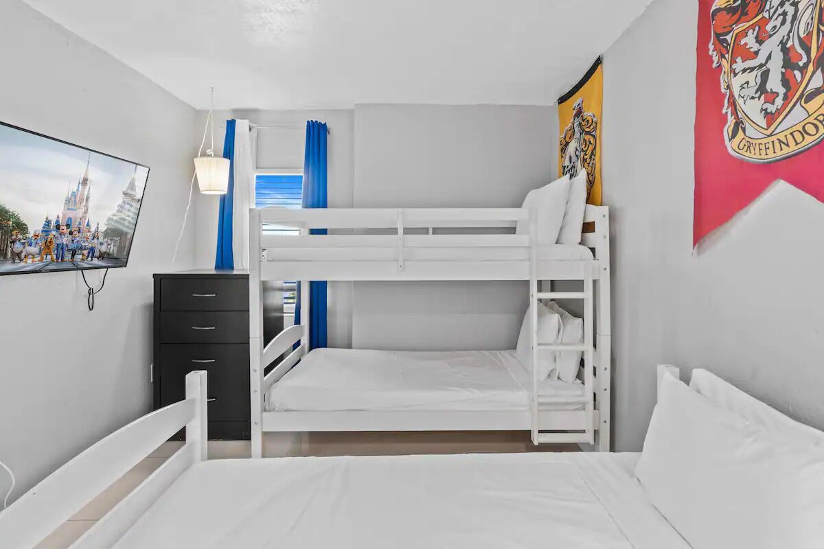 A bunk bed room with a television, a wardrobe, and a Gryffindor banner.