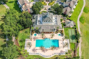 Vue aérienne d’une propriété résidentielle dotée d’une piscine, de plusieurs maisons et de pelouses bien entretenues.
