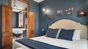 Une chambre à coucher avec un grand lit, une armoire en bois, une coiffeuse avec un miroir et un lustre.