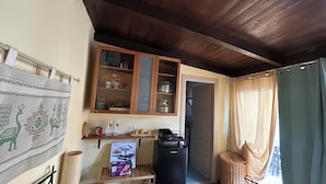 Eine kleine Küche mit Holzausstattung, einem Kühlschrank, einem Regal mit Küchenutensilien und einem Wandteppich.