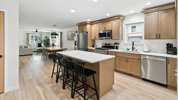 Una cocina moderna con armarios de madera, electrodomésticos de acero inoxidable y una isla central con taburetes de bar.