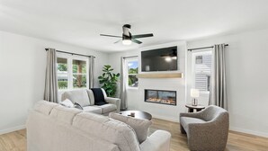 Una sala de estar moderna con un sofá, un sillón y una chimenea.
