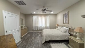 A bedroom with a bed, nightstands, a ceiling fan, and a window with curtains.