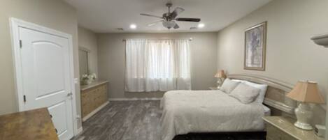 A bedroom with a bed, nightstands, a ceiling fan, and a window with curtains.