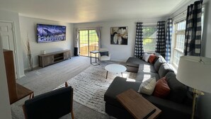 A living room with a sofa, coffee table, TV, and artwork. - The Lions Lair— Your ultimate spot for PSU football & all things Penn State (State College)