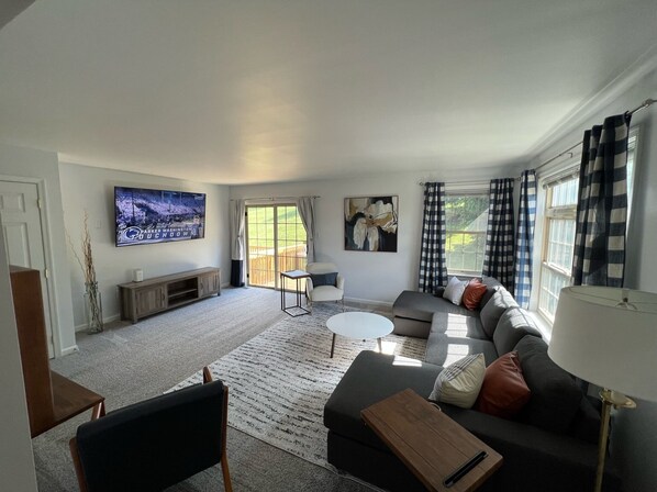 A living room with a sofa, coffee table, TV, and artwork.
