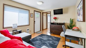 Een slaapkamer met een bed, bureau, stoel en een televisie aan de muur.
