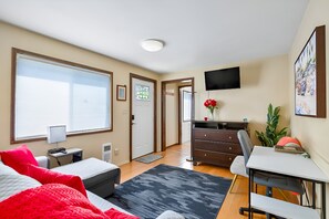 Un dormitorio con cama, escritorio, silla y televisor en la pared.
