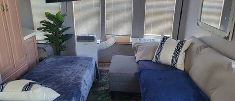 Une chambre avec deux lits, une télévision et une fenêtre avec des stores.