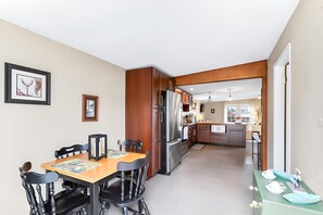 Eine moderne Küche mit Holzschränken, einem Edelstahlkühlschrank und einem Essbereich mit Holztisch und -stühlen.