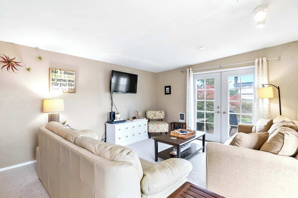 A living room with a sofa, a coffee table, a TV, and a window with curtains.