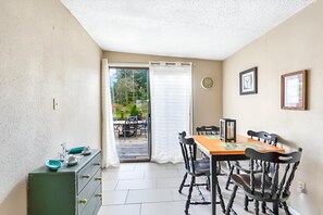 A dining area with a table and chairs, a green cabinet, and a view through a glass door to an outdoor patio.
