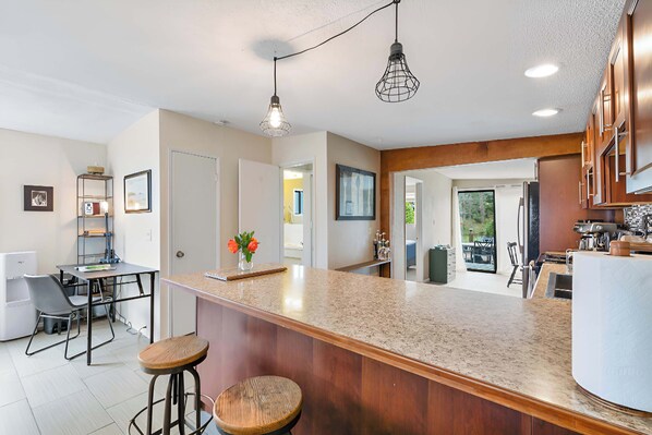 Una cocina moderna con una isla central, taburetes de bar e iluminación colgante.