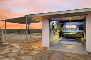 A building with a covered outdoor area, a pool table, and a view of the desert landscape. - Mid-Century Views - 2 Min to JTNP - Retro Vibes (Twentynine Palms)