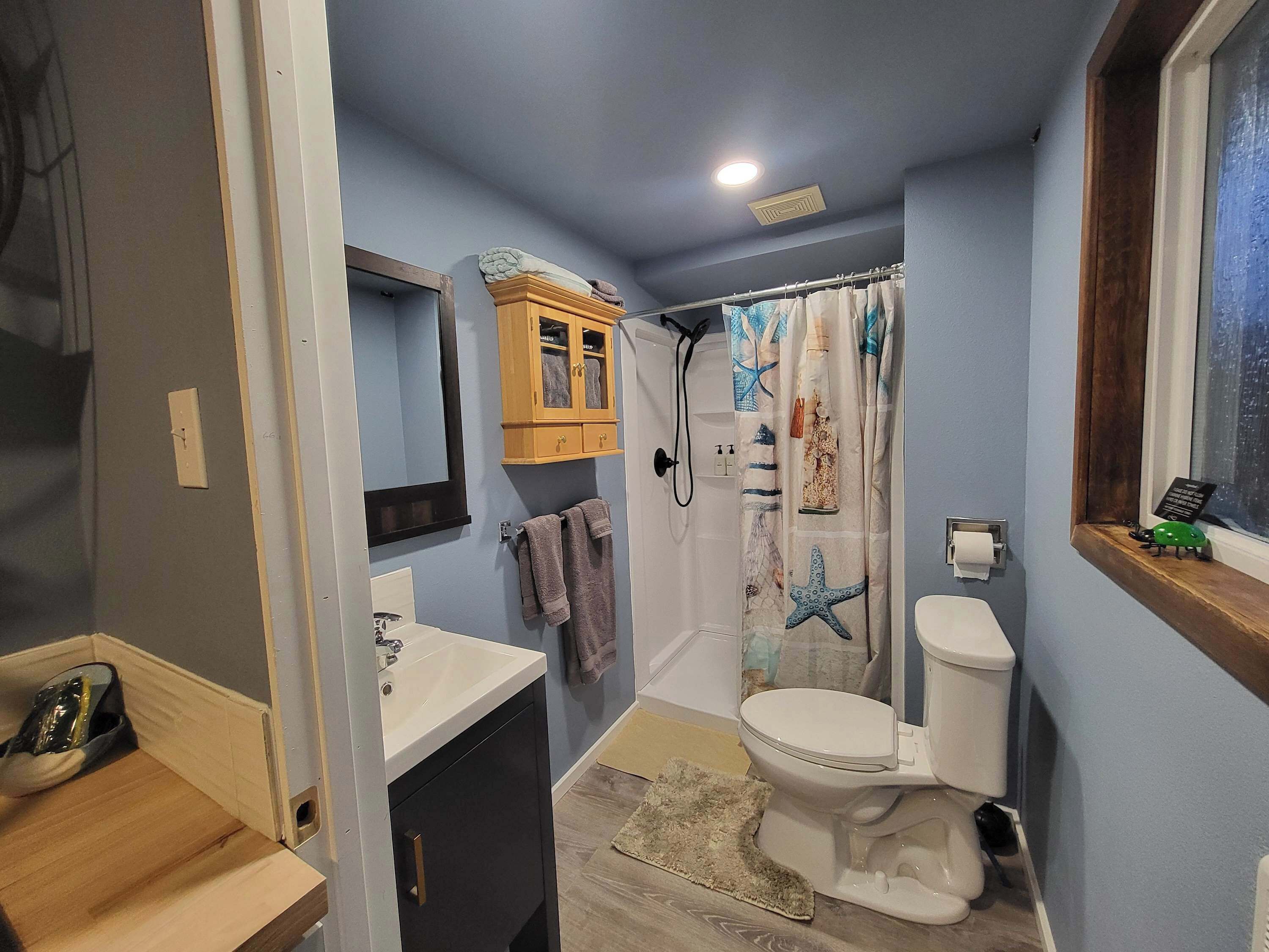 Une salle de bain équipée de toilettes, d’un lavabo, d’une douche et d’un meuble en bois.
